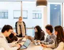 une professeur et des étudiants devant leur ordinateur autour d'une table