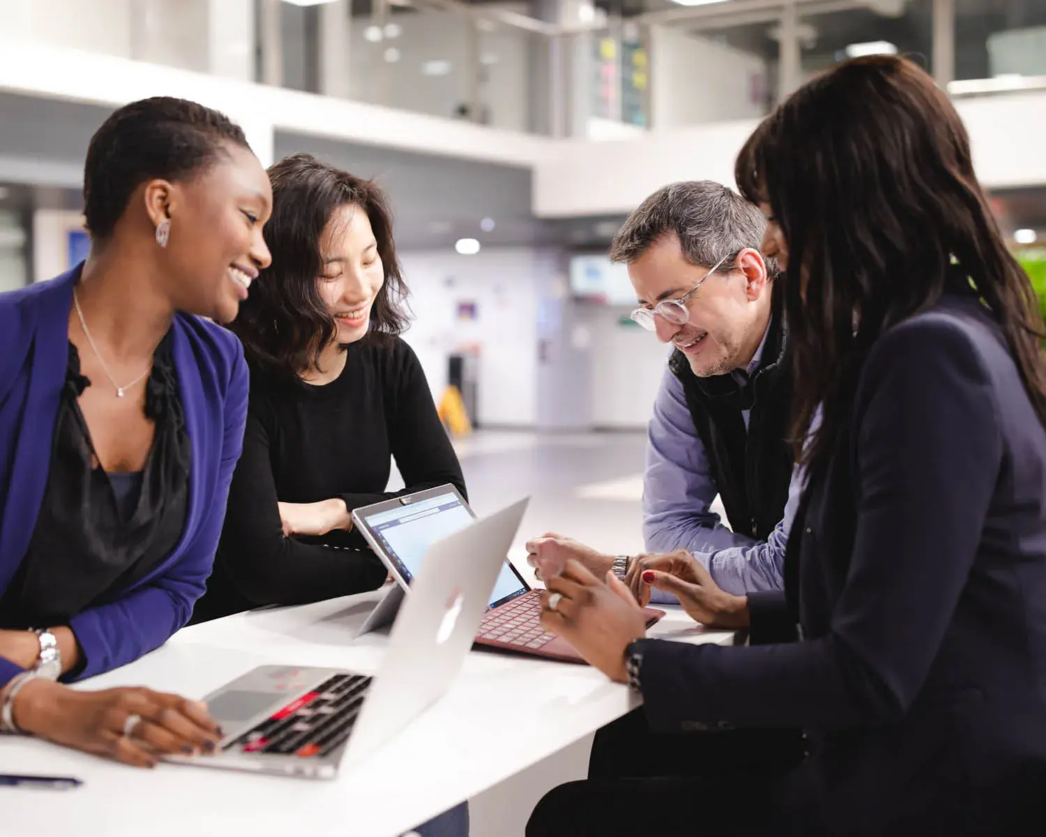 quatre personnes travaillent ensemble devant deux ordinateurs