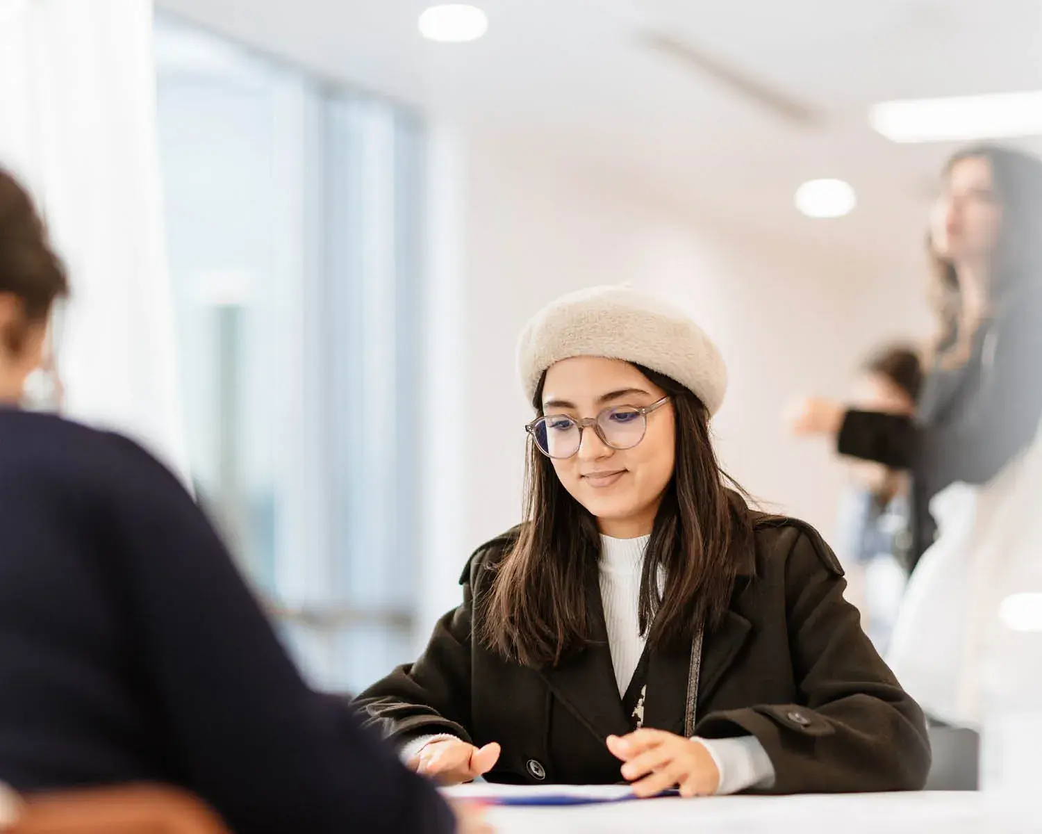 une jeune fille avec un berret et des lunettes passe un entretien