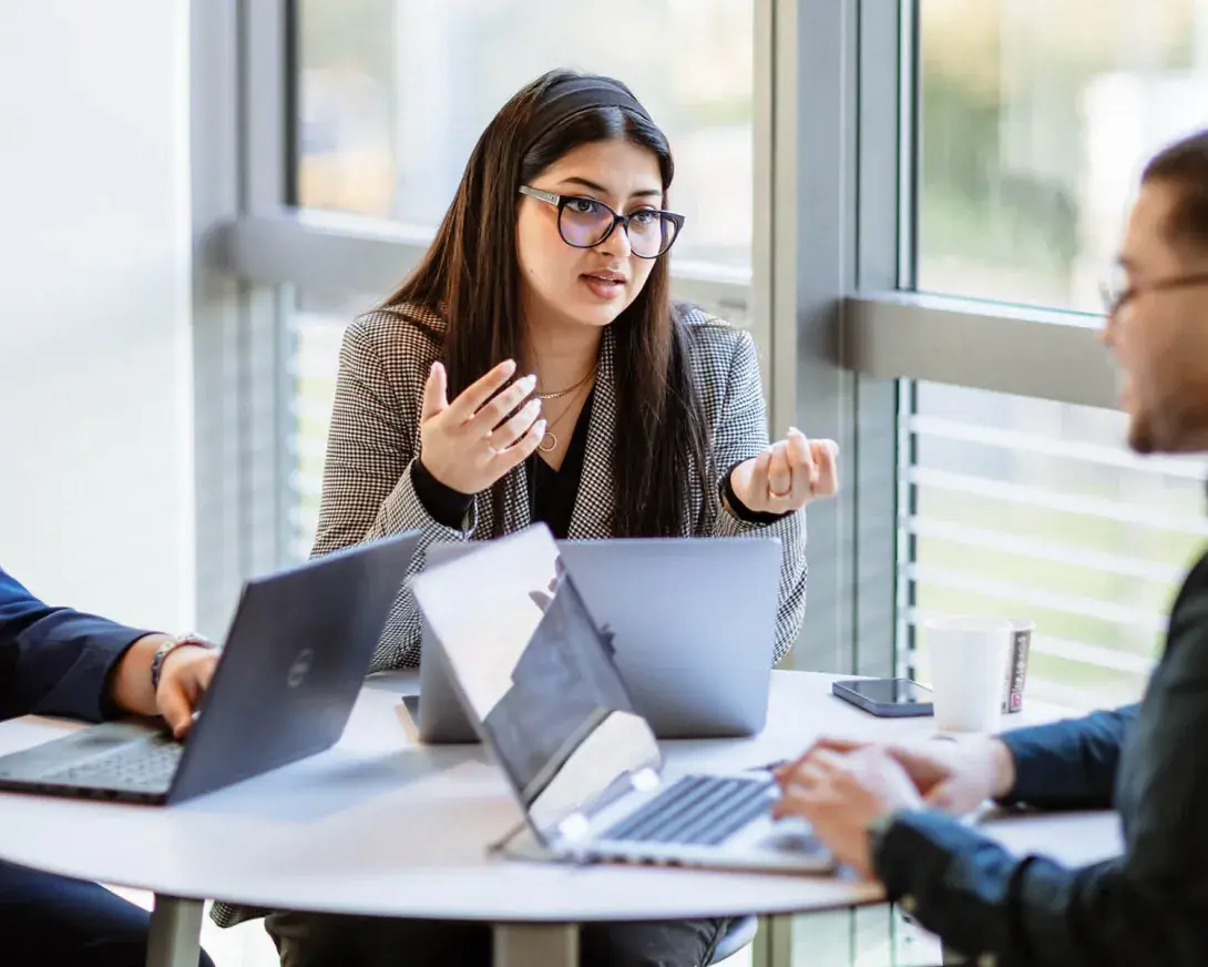des étudiants discutent autour d'une table avec des ordinateurs