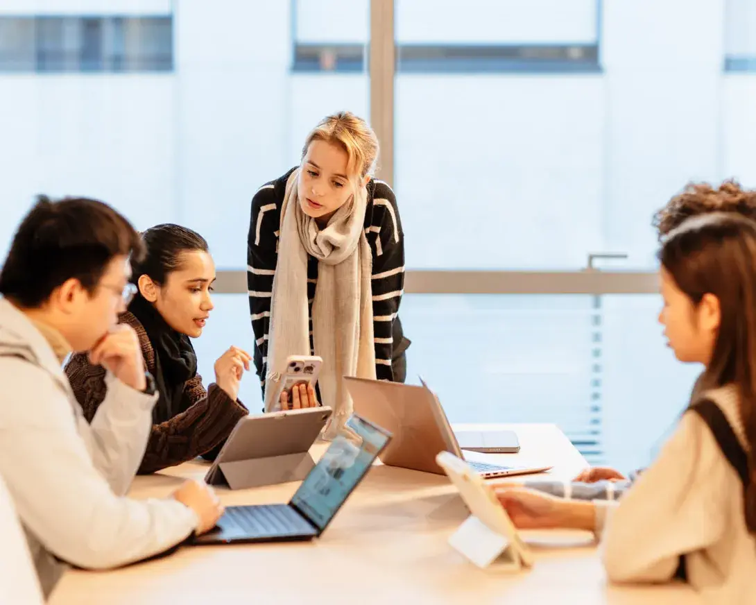 une professeur et des étudiants devant leur ordinateur autour d'une table