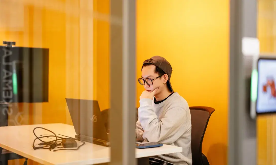 un étudiant seul sur son ordinateur dans une salle de travail