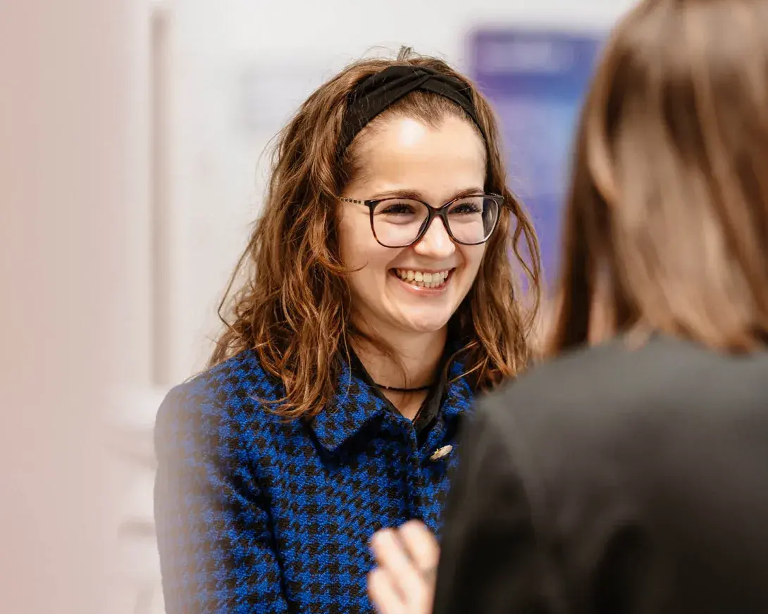une femme avec des lunettes et un bandeau souriant à une autre 