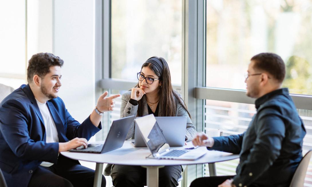 des étudiants discutent autour d'une table avec des ordinateurs
