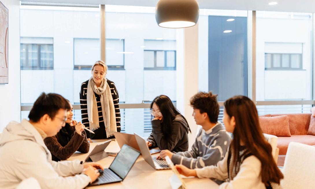 une professeur et des étudiants devant leur ordinateur autour d'une table