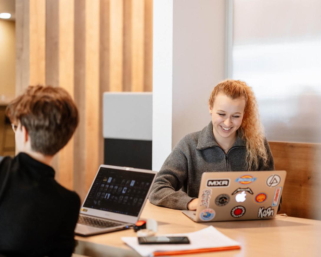 deux étudiants souriant devant leur ordinateur